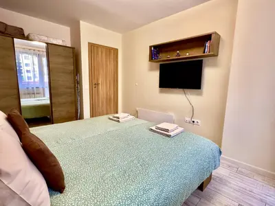a bedroom with a bed and a flat screen tv at Petkovi Аpartments, Borovets Gardens - One-bedroom and Two-bedroom apartments in Borovets