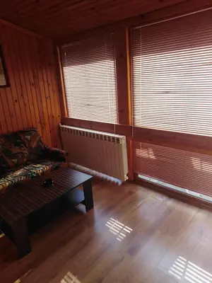 a room with a couch and a table and windows at Вила Родопи in Dospat