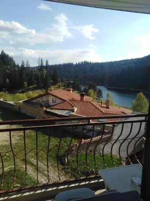 a view from the balcony of a house with a lake at Вила Родопи in Dospat