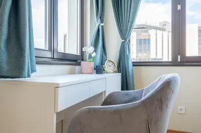 a desk and a chair in a room with windows at Sunrise 1BDRM View Apartment NDK Congress Centre in Sofia