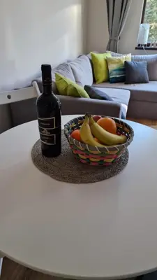 a bottle of wine and a bowl of fruit on a table at Pine Tree Apartment / Borovets Gardens in Borovets