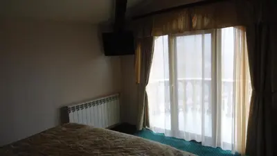 a bedroom with a bed and a large window at Family Hotel Shipkovo in Shipkovo