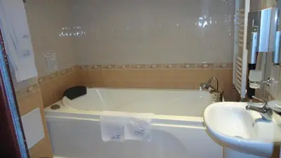 a bathroom with a white tub and a sink at Family Hotel Shipkovo in Shipkovo