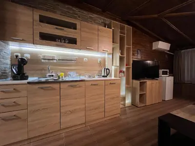 a large kitchen with wooden cabinets and a television at Georgievi Apartments Sandanski in Sandanski