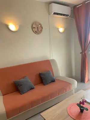 an orange couch in a room with a clock on the wall at City Residence Apartments Sofia in Sofia