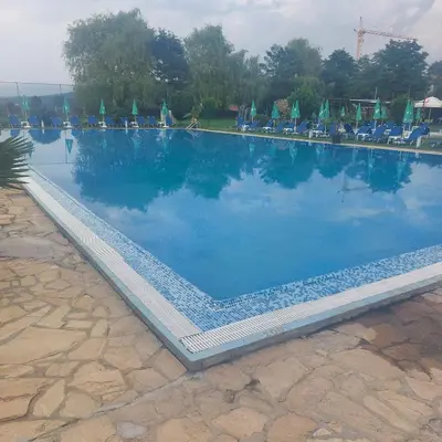 a large swimming pool with chairs and blue water at Комплекс Александьр между Банско и село Бяня in Bansko