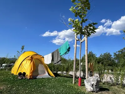a yellow tent in the grass next to a tree at 7 Lakes camping in Sapareva Banya