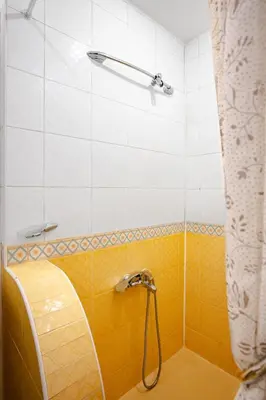 a shower with a yellow and white tiled wall at Charming Studio on Vitosha Street by Flat Mаnager in Sofia
