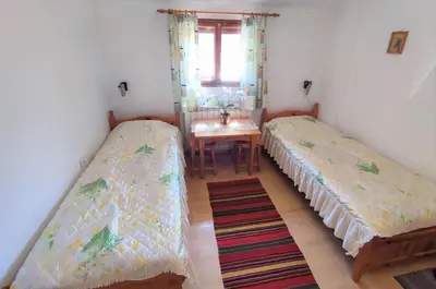 two beds in a room with a table and a window at Къща Чолаков и син - стаи за гости in Devin