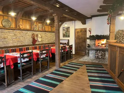 a restaurant with a table and chairs and a brick wall at Кондеви къщи in Kovachevitsa
