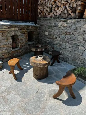 a patio with tables and chairs and a stone fireplace at Кондеви къщи in Kovachevitsa