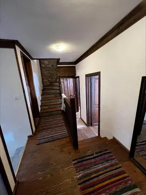 a staircase in a house with wooden floors and white walls at Кондеви къщи in Kovachevitsa