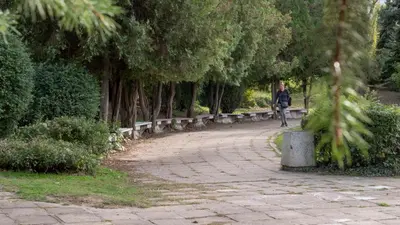 a woman walking down a path in a park with trees at Луксозно студио One Place in Sofia A1 - Лозенец in Sofia