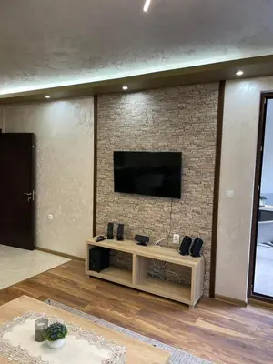 a living room with a television on a brick wall at Апартамент ВАНЕСА in Velingrad