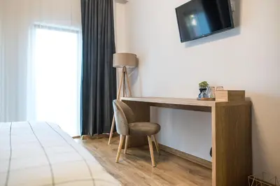 a desk with a chair and a television on a wall at Deluxe Central Rooms in Karlovo