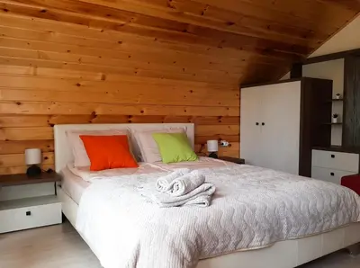 a bedroom with a white bed with wooden walls at ВИЛА Belle Vie in Beli Iskar