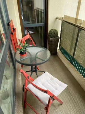 a glass table and a red chair on a balcony at Modern & Central 1BR Apartment with lovely terrace in Plovdiv