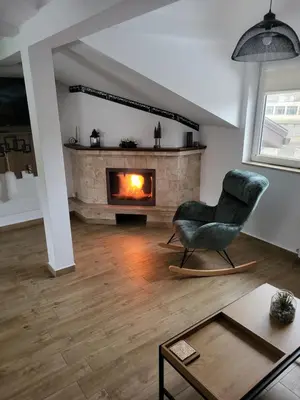 a living room with a chair and a fireplace at Къща за гости-Ганеви in Zmeitsa