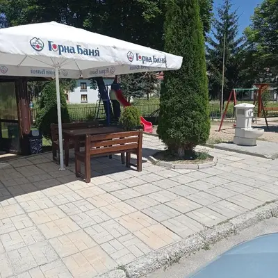 a picnic bench under a white umbrella next to a playground at Къща за гости-Ганеви in Zmeitsa