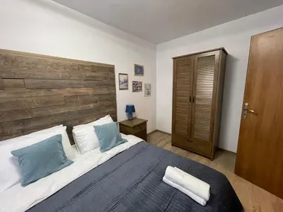 a bedroom with a large bed with a wooden headboard at Апартамент Стил in Chepelare