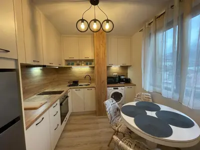 a kitchen with a table and a kitchen with white cabinets at Апартамент Стил in Chepelare