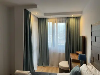a bedroom with a window with green curtains at Апартамент Стил in Chepelare
