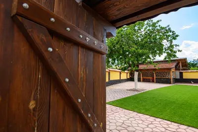 a wooden fence with a green lawn behind it at Guest House Dinaya in Dobrinishte