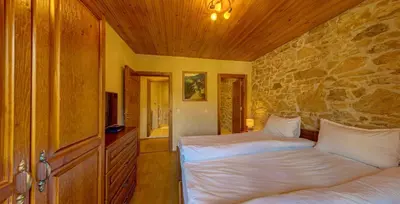 a bedroom with two beds and a stone wall at Къща за гости 