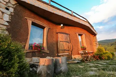 a house with two windows and a table and chairs at Панорама хаус Лещен и еко къщи Дървена и Землянка in Leshten