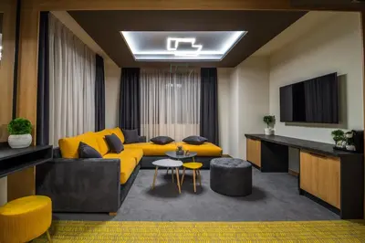 a living room with a yellow couch and a tv at EMAR HOTEL & SPA in Sapareva Banya