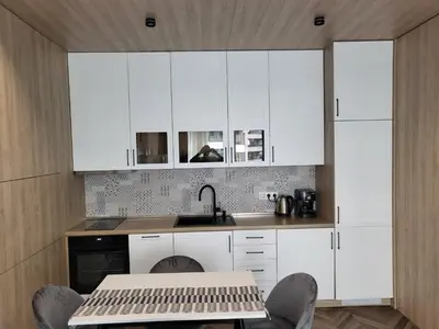 a kitchen with white cabinets and a sink and a table at New luxury apartment next to subway with garage in Sofia
