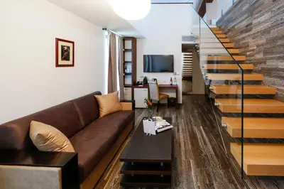 a living room with a brown couch and stairs at Uva Nestum Wine & SPA in Gotse Delchev