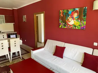 a living room with a white couch and red walls at Червената Шапчица Апартамент Гранд Манастира in Pamporovo