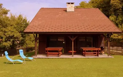 a gazebo with wooden tables and chairs in the grass at Boyana Vacation Houses in Cherni Vit