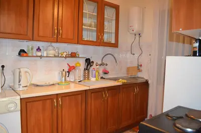 a kitchen with wooden cabinets and a white refrigerator at Villa Bella - A Rila Monastery Adventure in Kocherinovo
