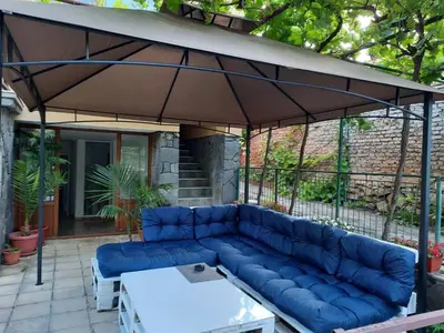 a blue couch under an umbrella on a patio at Апартаменти за гости ,,Тракия'' in Hisarya