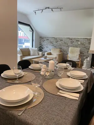 a dining table with plates and wine glasses on it at Private Apartment Laplandia 77 (Pamporovo, Bulgaria) in Pamporovo
