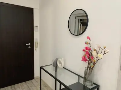 a mirror and a vase with flowers on a glass table at Nordic Style Apartment with Parking place in Sofia