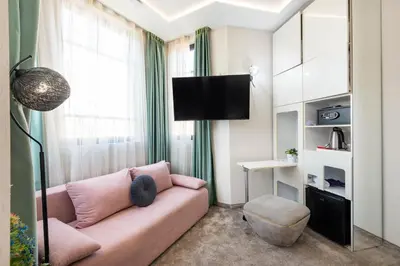 a living room with a pink couch and a tv at Aurora Hills Hotel in Plovdiv