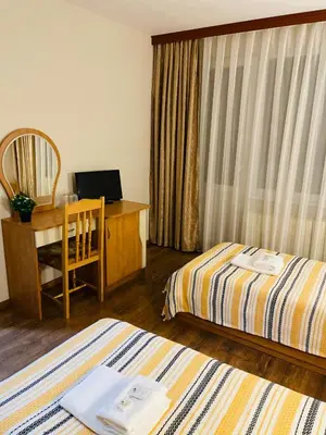 a hotel room with two beds and a desk with a computer at Хотел Лагуна in Dospat