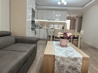 a living room with a couch and a table with flowers at Къща за гости ТАТЯНА / GUEST HOUSE TATIANA in Petrich