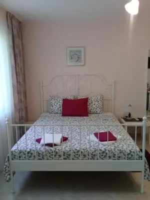 a bedroom with a white bed with two red pillows at Sandanski Peak Guest Rooms in Sandanski