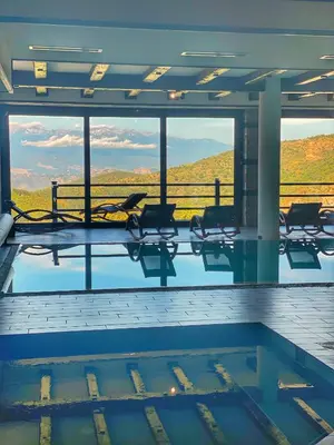 a swimming pool with chairs and a view of a mountain at Hotel Leshten in Leshten