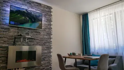 a living room with a table and a tv on a brick wall at KLEPALSKI - Mountain Studio in Borovets