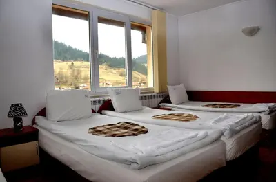 three beds in a room with a window at Family Hotel Daisy in Borino