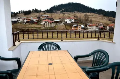a wooden table and chairs on a balcony with a view at Family Hotel Daisy in Borino