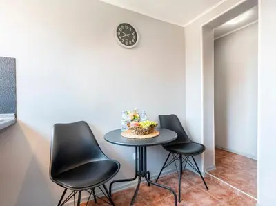 a table with three black chairs and a clock on a wall at Lovely 1-bedroom apartment in the center of Sofia in Sofia