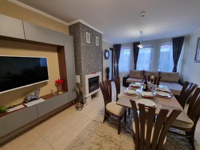 a living room with a dining table and a television at Гранд Манастира Лукс in Pamporovo