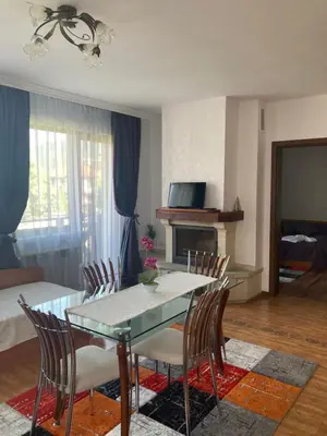 a dining room with a table and chairs and a living room at GD Apartament in Bansko