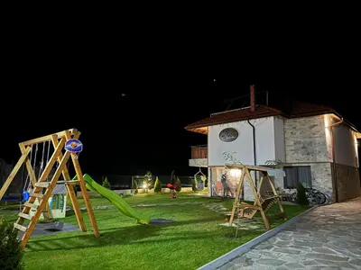 a yard with a playground with a house at night at 4U LUXURY VILLA in Dospat
